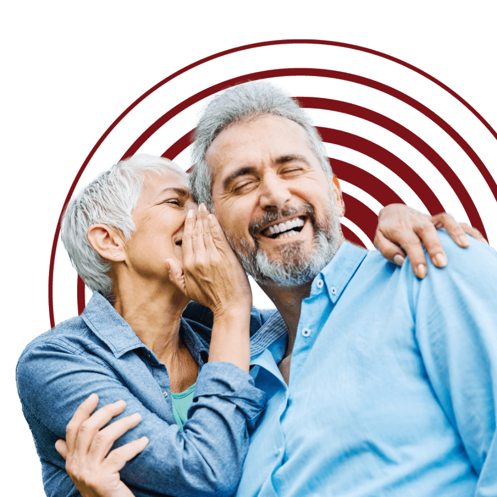 A couple laughing together &mdash; enjoying conversation and connection again after addressing hearing loss with Revolution Hearing